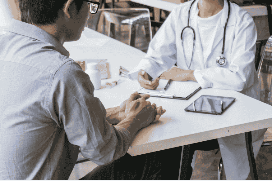Médico e paciente em consulta discutindo resultados apoiados por IA e registro eletrônico de saúde.
