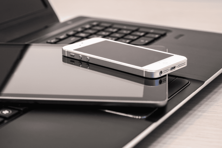 Notebook, tablet e smartphone sobre a mesa representando os dispositivos que devem ser protegidos pela estratégia de Zero-Trust em pequenas empresas.